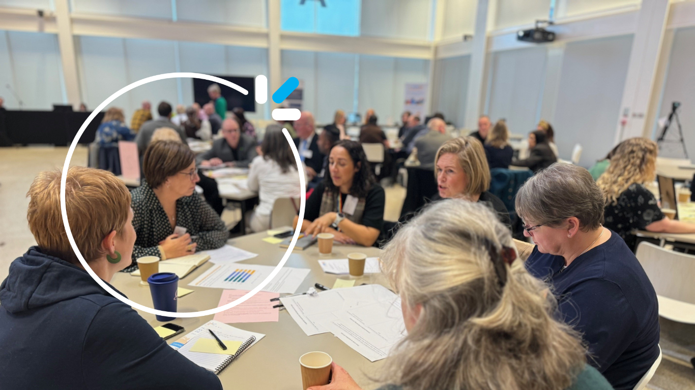 Alison sitting at a table with VONNE colleagues and conference attendees. She is listening to the women beside her speaking.