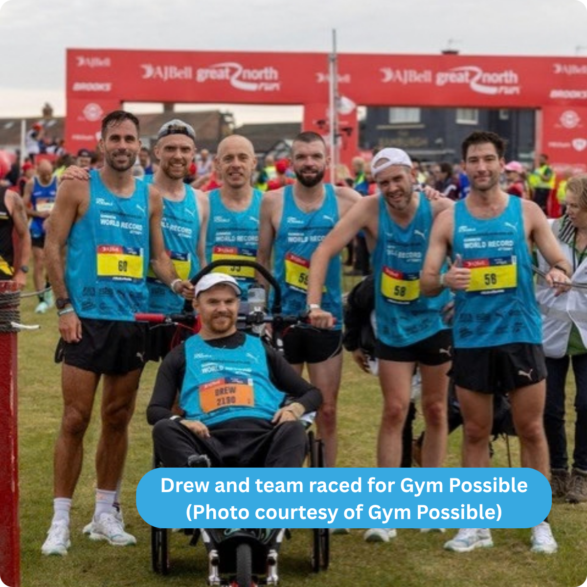 Photo of Drew seated in his wheelchair, surrounded by his running team of 6 men at the race finish line