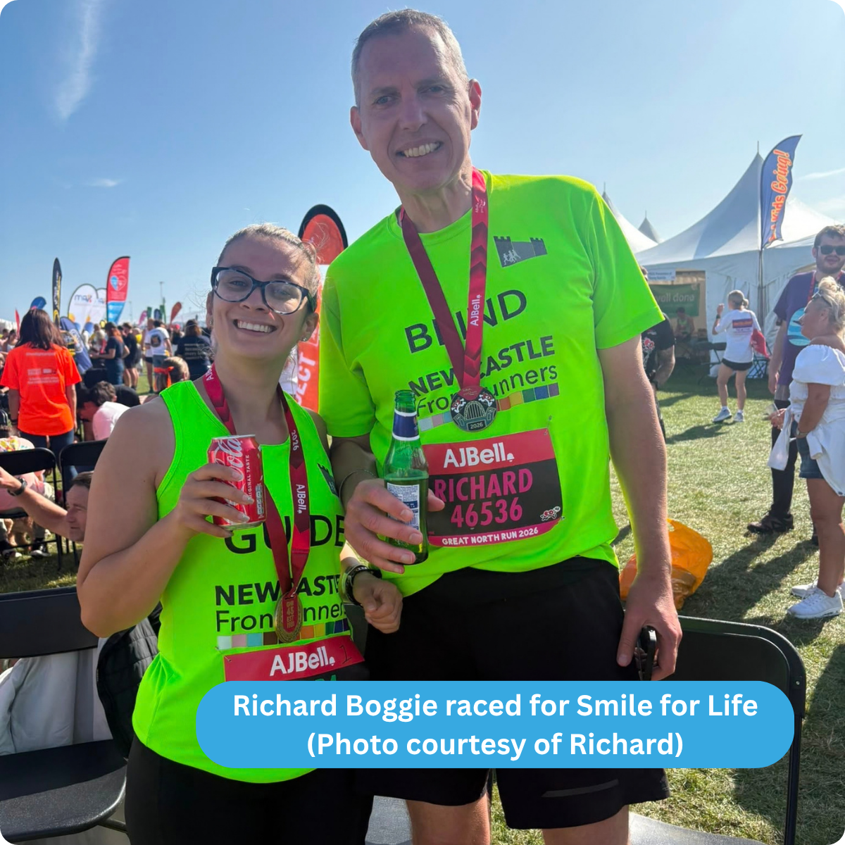 Photo of Richard standing next to Laura his running guide, both holding a beverage following the end of the race