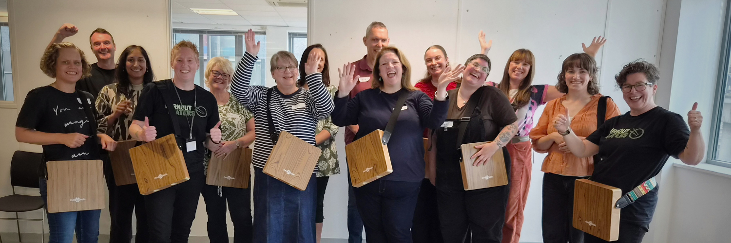 The VONNE team looking joyful after a drumming session. Standing and smiling for the camera with arms in the air and cajon drums strapped to our shoulders