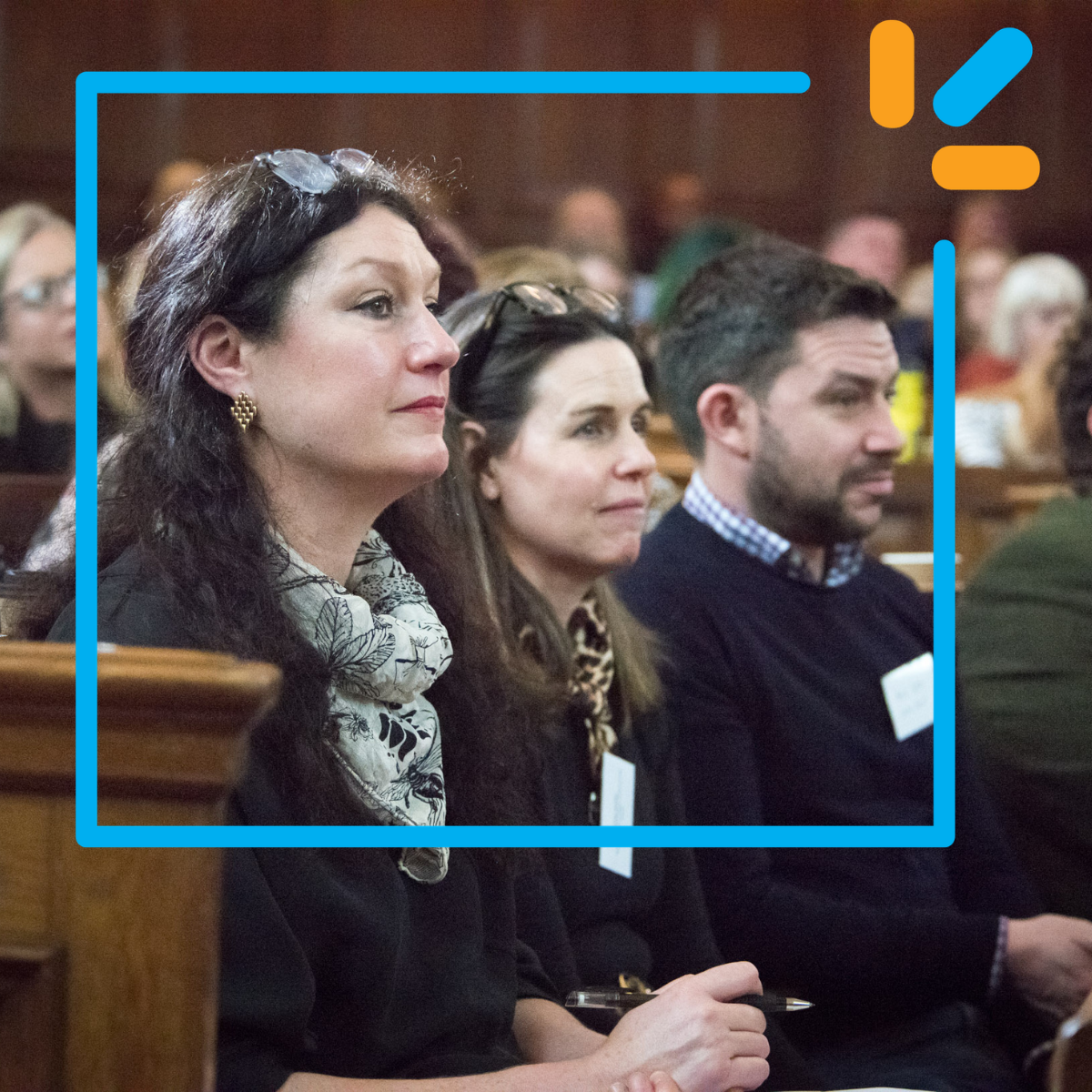 Photograph of attendees at From the Ground Up, sat in a row looking off camera towards a speaker on stage